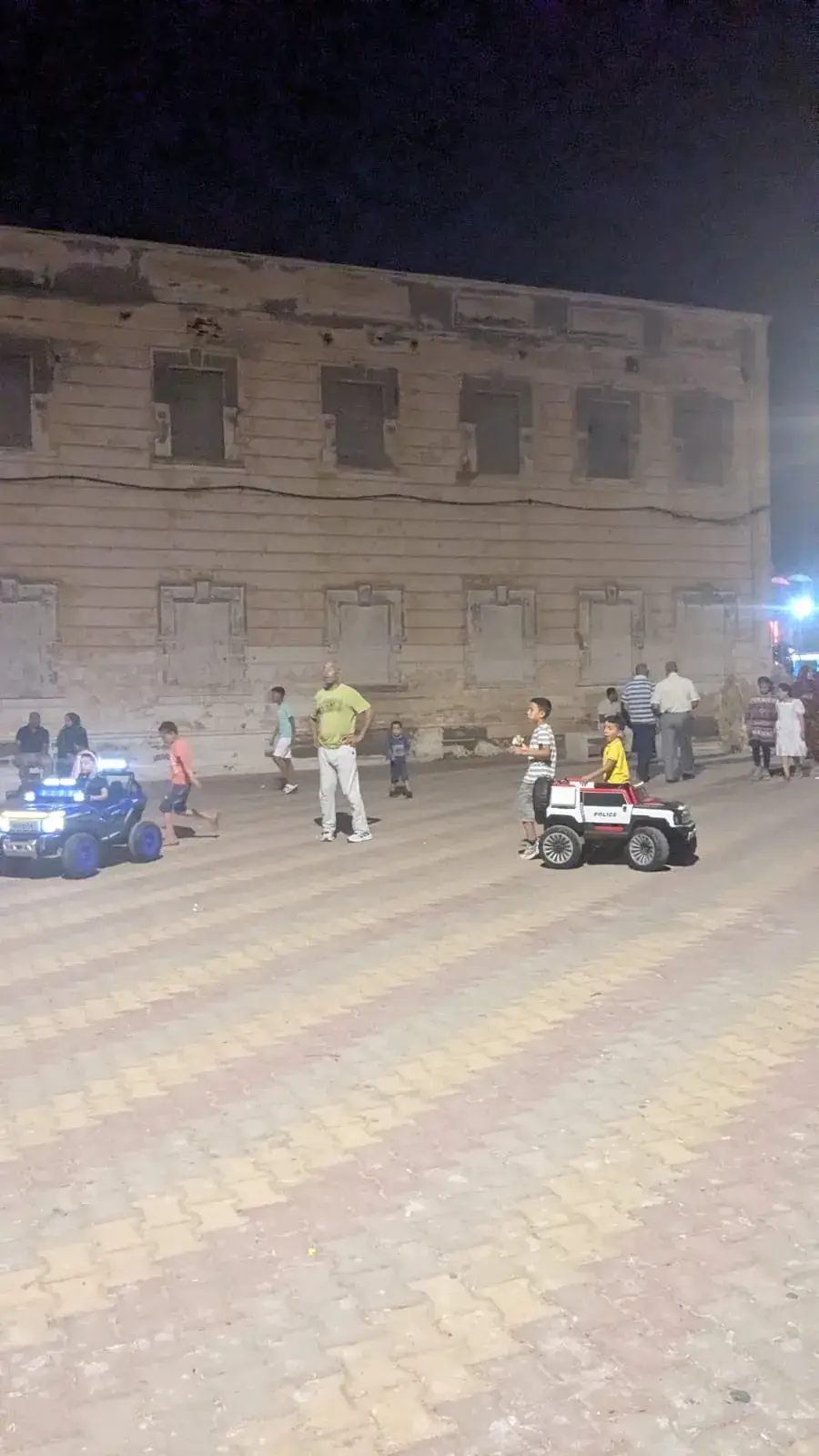 Children riding electric toy cars in the square behind the former Spanish consulate in Sidi Ifni at night