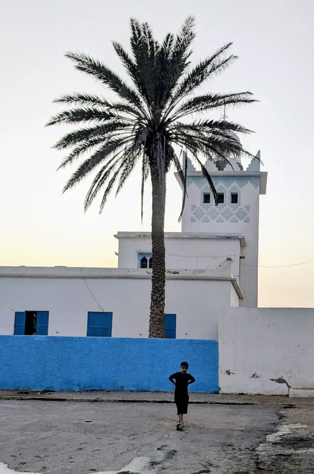 Spanish-period lighthouse in Sidi Ifni behind a palm tree at dusk